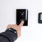 Finger adjusting a modern digital thermostat