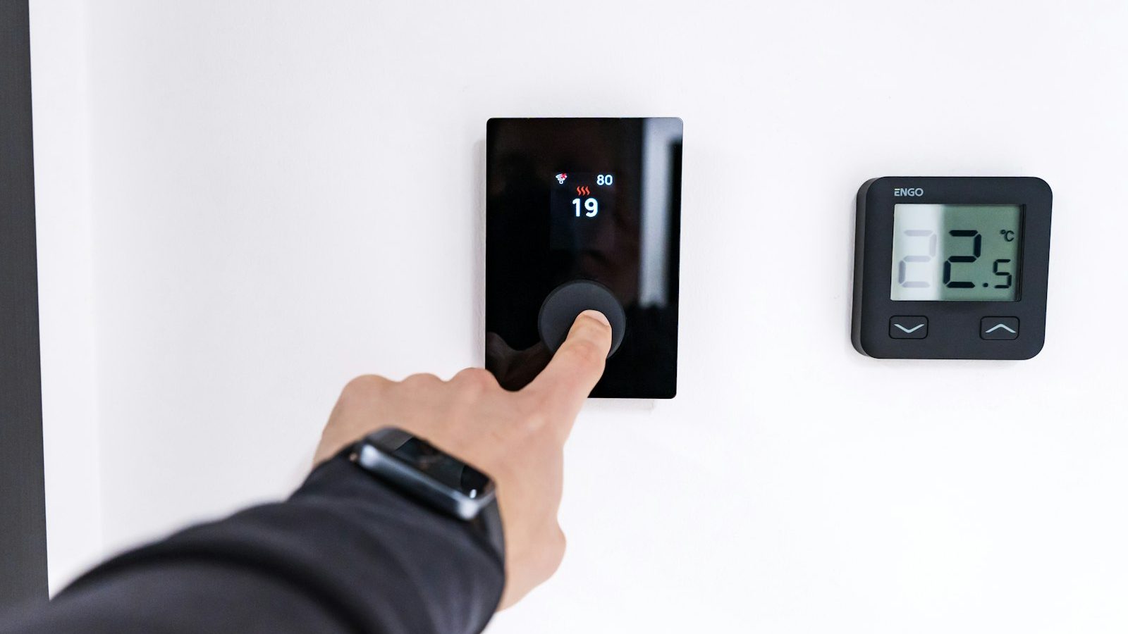Finger adjusting a modern digital thermostat