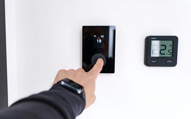 Finger adjusting a modern digital thermostat