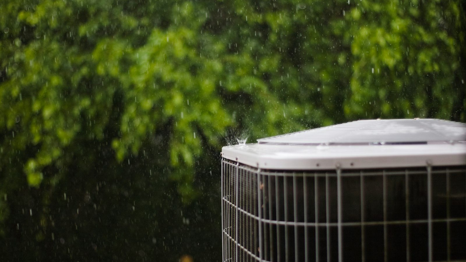 Close-up of a heat pump condenser outdoors in the rain