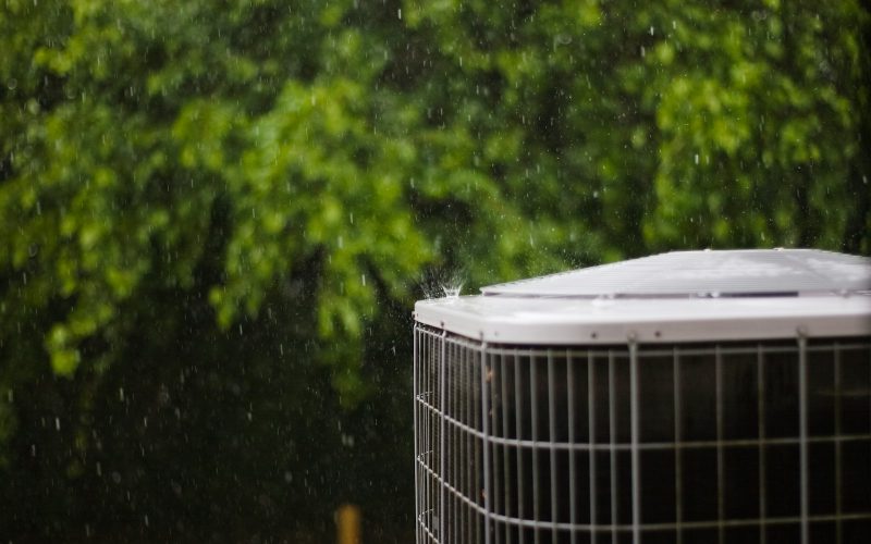 Close-up of a heat pump condenser outdoors in the rain