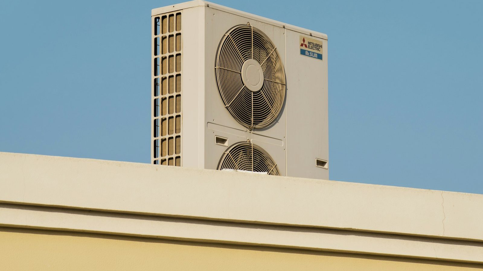 Heat pump condenser on a rooftop against a blue sky