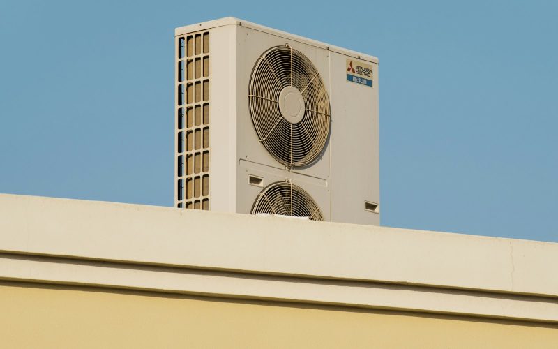 Heat pump condenser on a rooftop against a blue sky