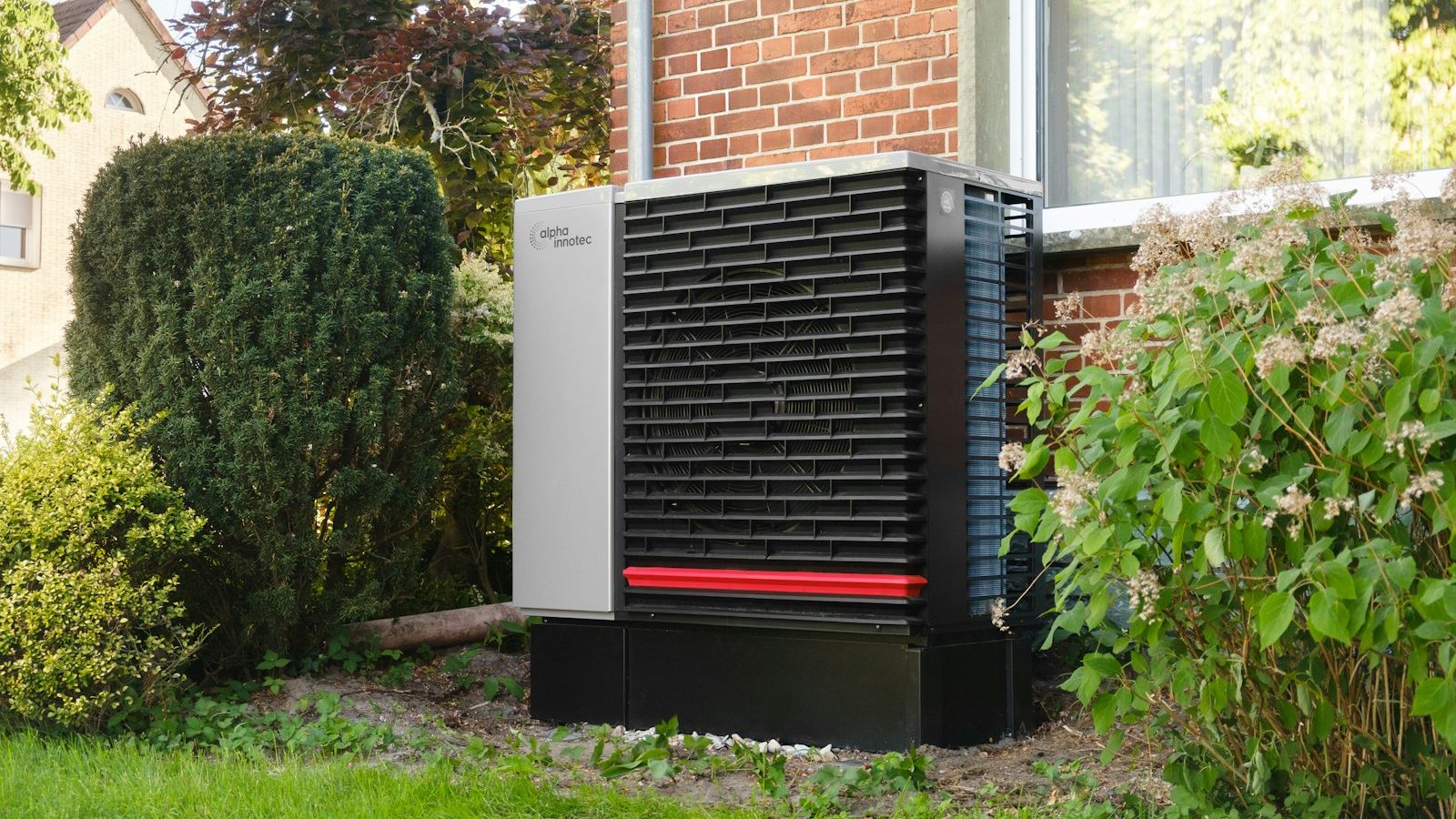 Outdoor heat pump unit installed next to a brick house
