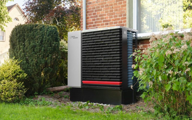 Outdoor heat pump unit installed next to a brick house