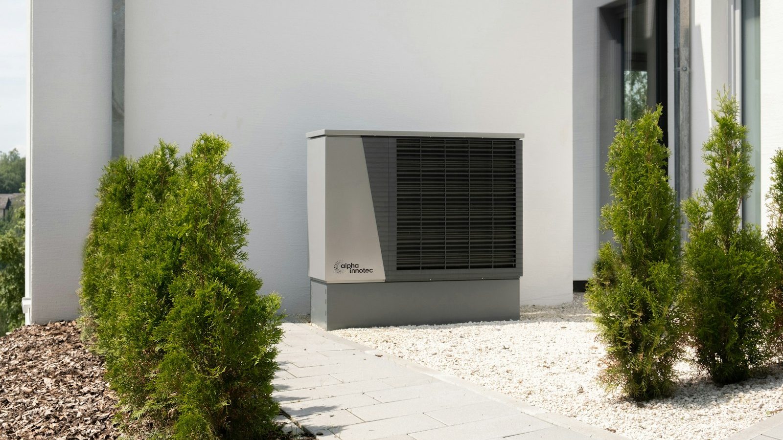 Heat pump outdoor unit on the side of a modern white house