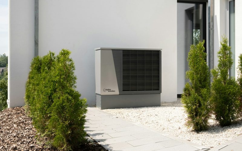 Heat pump outdoor unit on the side of a modern white house