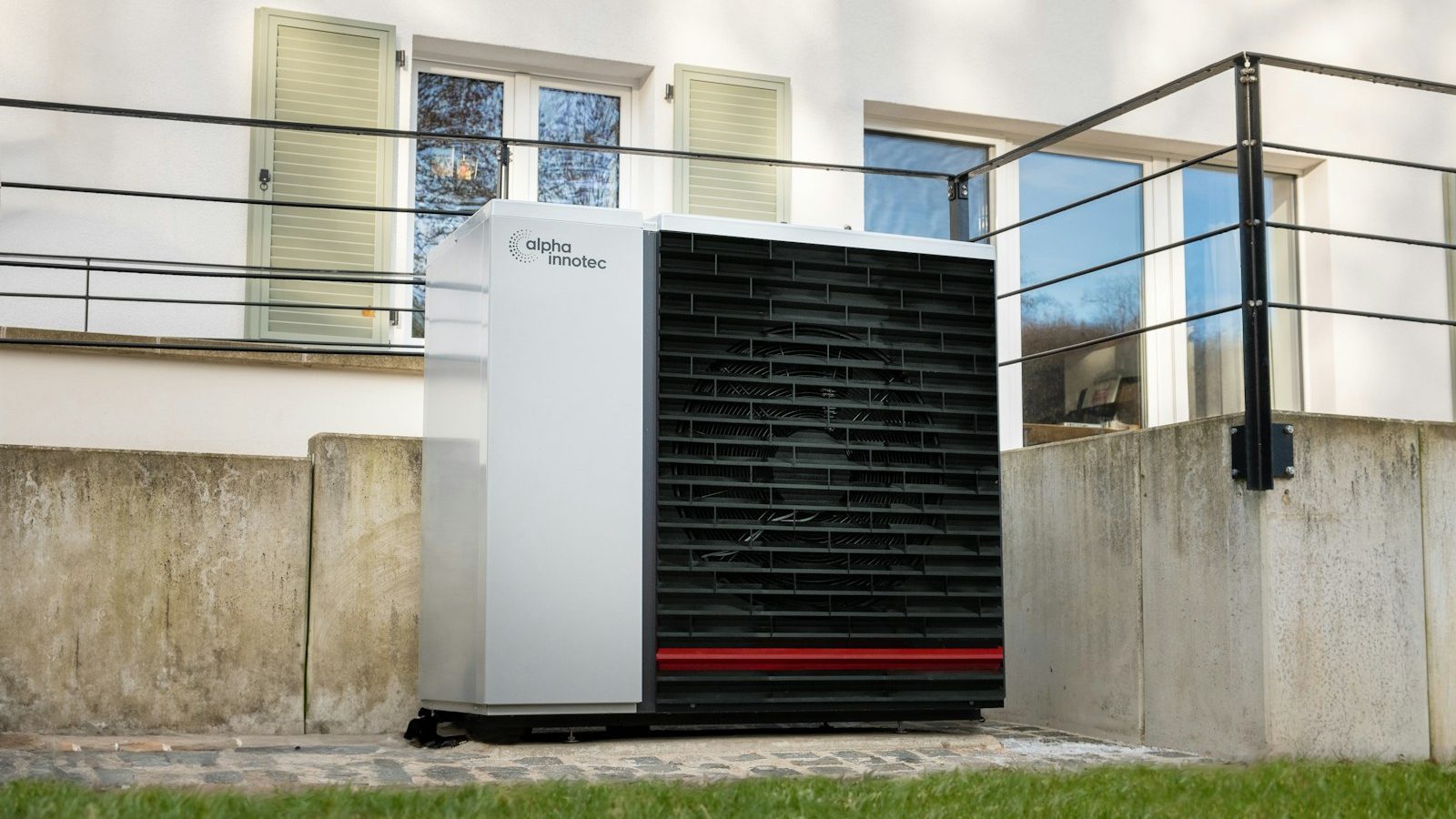 Heat pump outdoor unit in front of a house patio