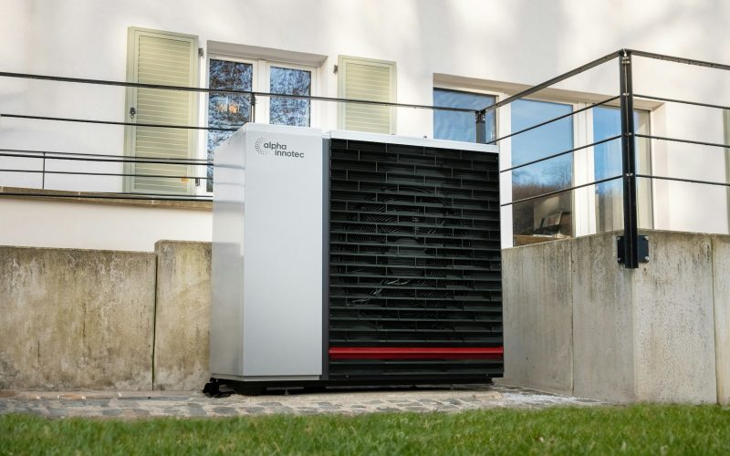 Heat pump outdoor unit in front of a house patio