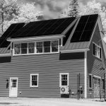 House with rooftop solar panels in a forest setting