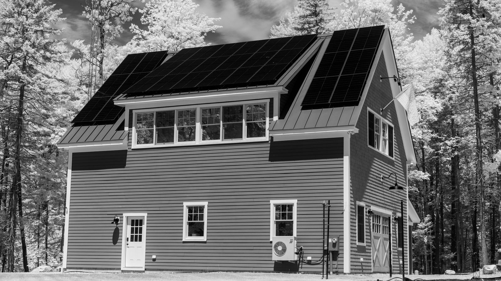 House with rooftop solar panels in a forest setting