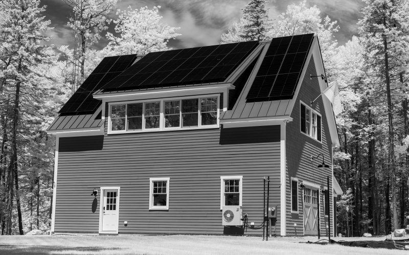 House with rooftop solar panels in a forest setting