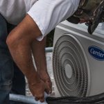 HVAC technician servicing a heat pump outdoor unit