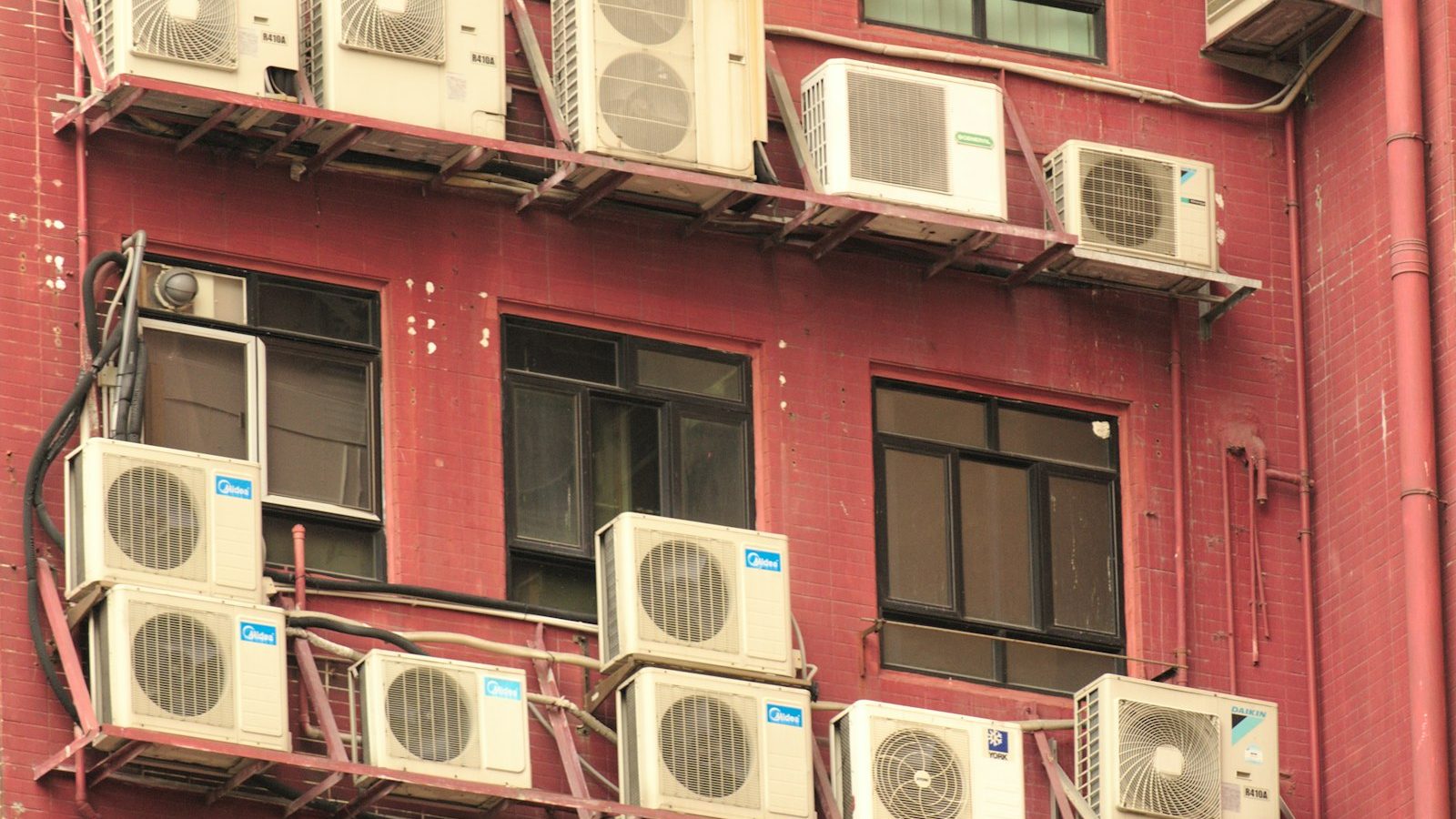 Many air conditioner condenser units on an apartment facade