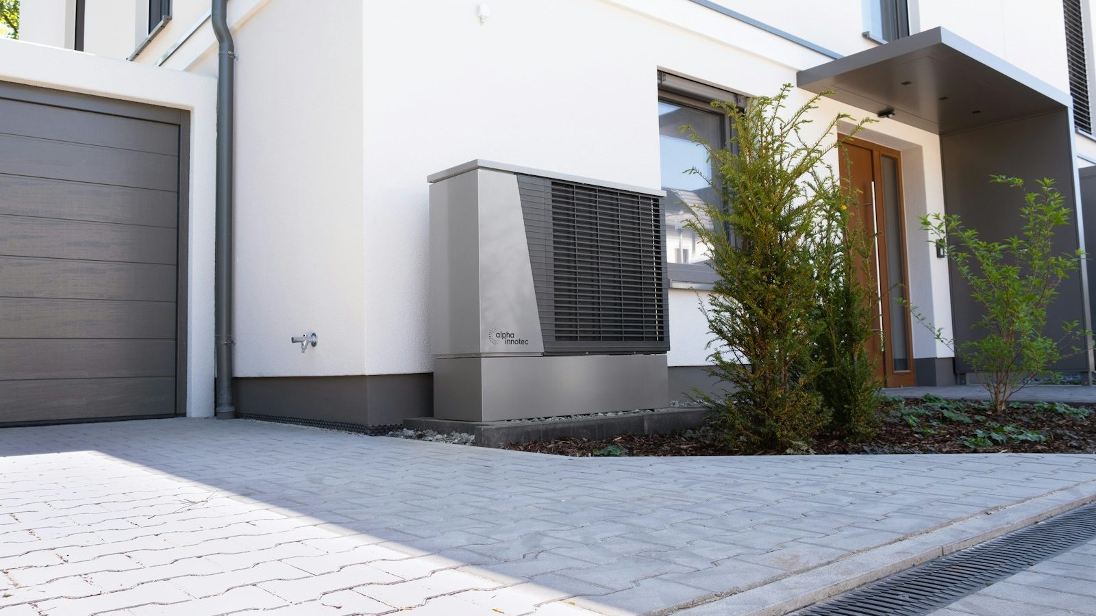 Modern home exterior with an air-source heat pump outdoor unit beside the garage