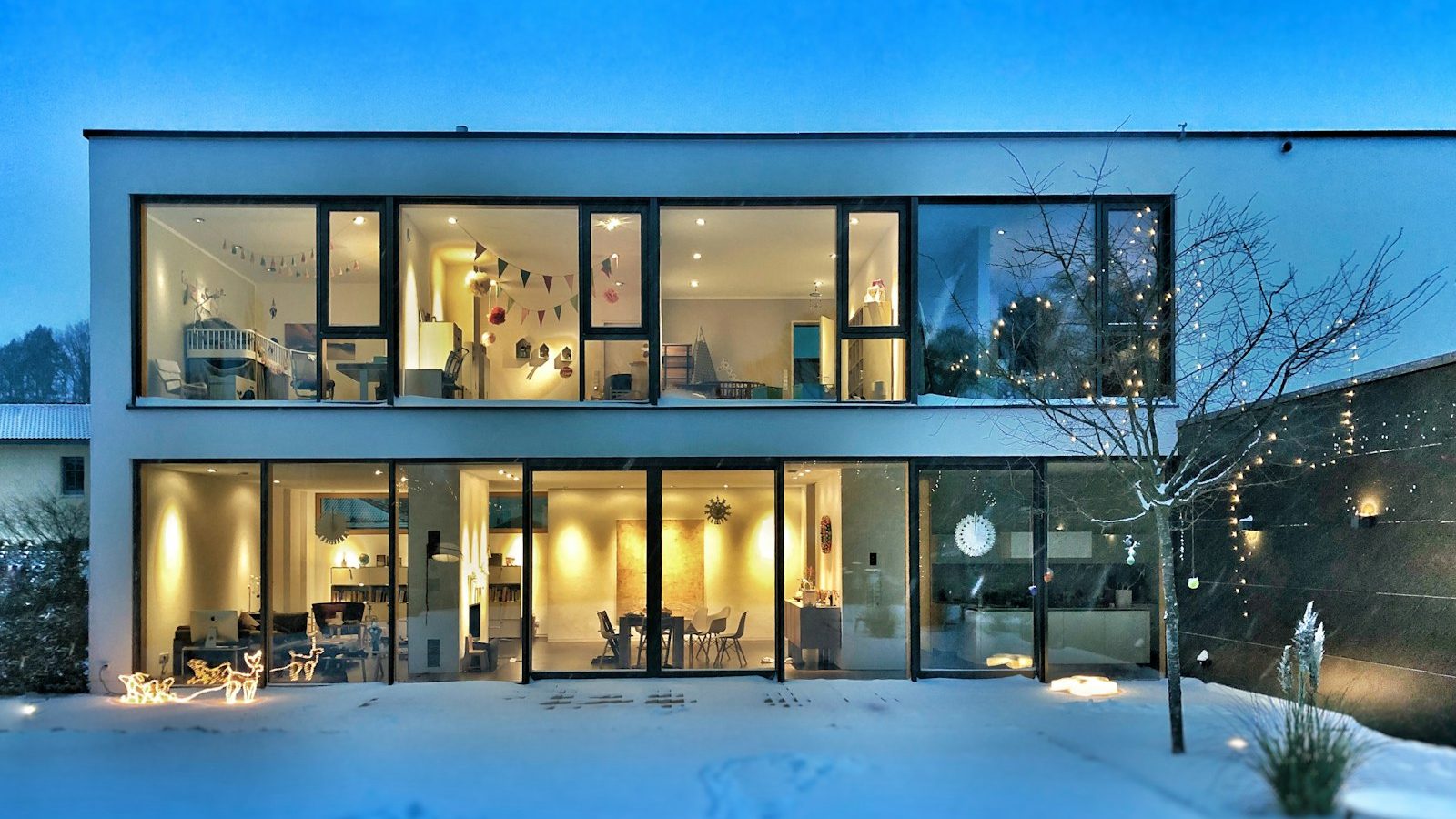 Modern house lit up on a winter evening with snow