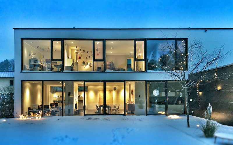 Modern house lit up on a winter evening with snow