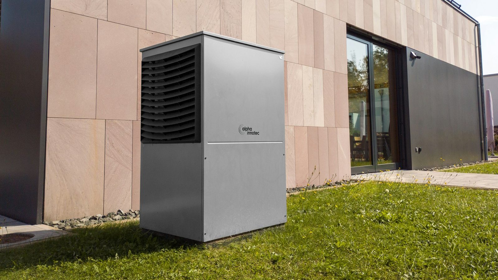 Modern outdoor heat pump unit next to a stone-clad building