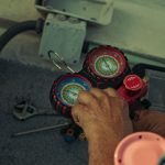 Technician adjusting refrigerant manifold gauges