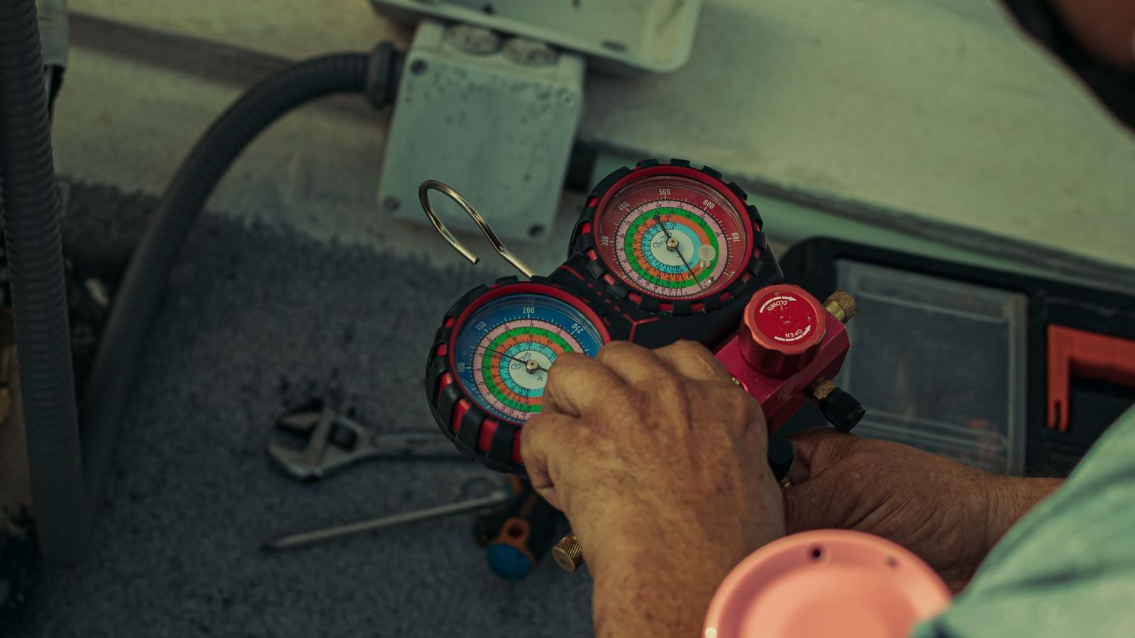 Technician adjusting refrigerant manifold gauges