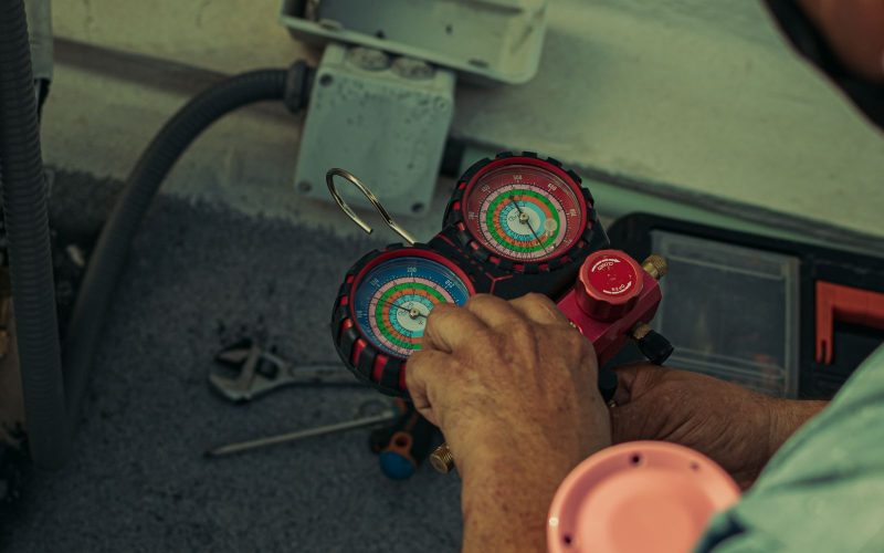 Technician adjusting refrigerant manifold gauges